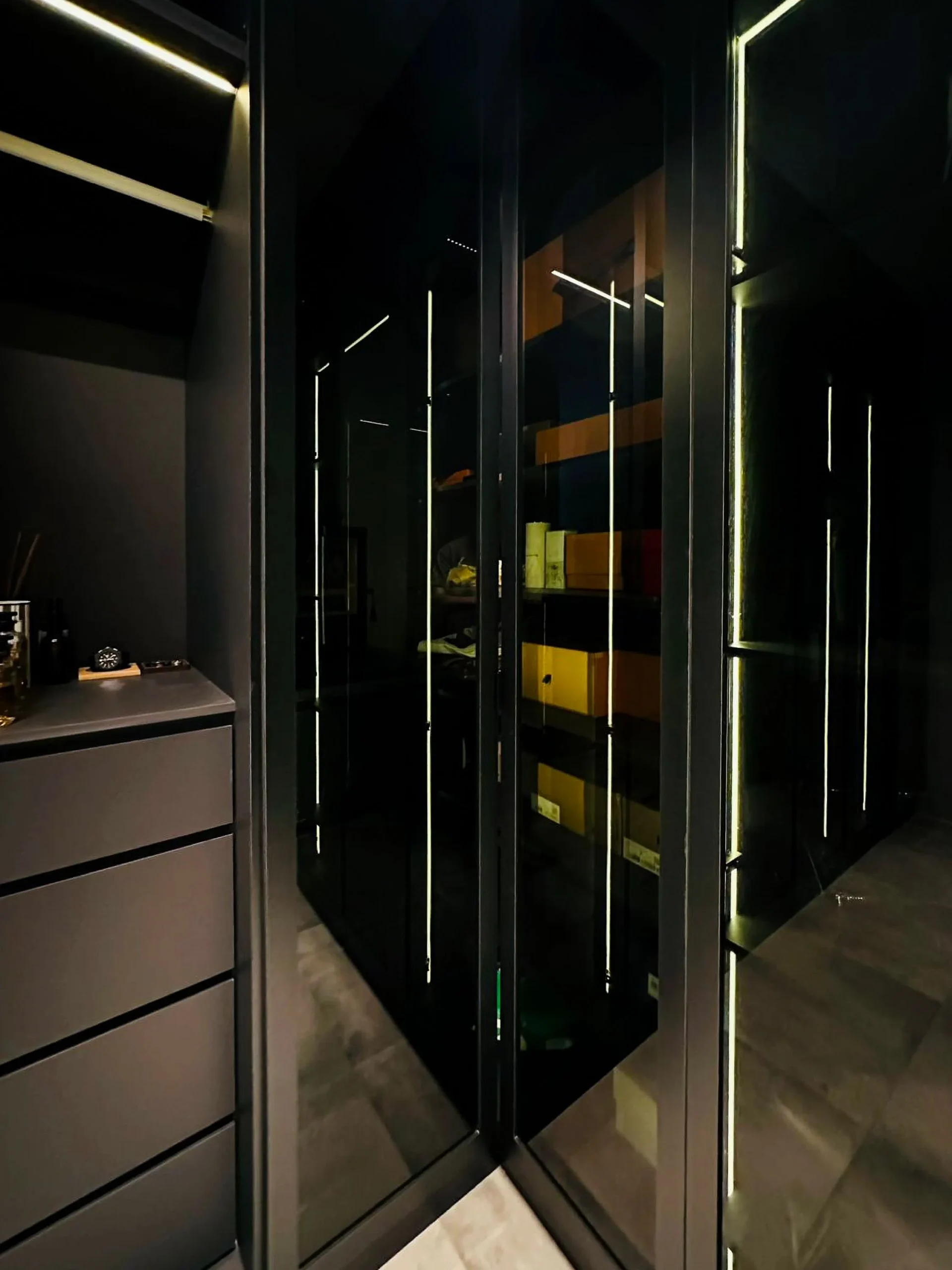 Tinted-glass wardrobe doors displaying the owners' collection under LED light, 332 Hougang Ave 5